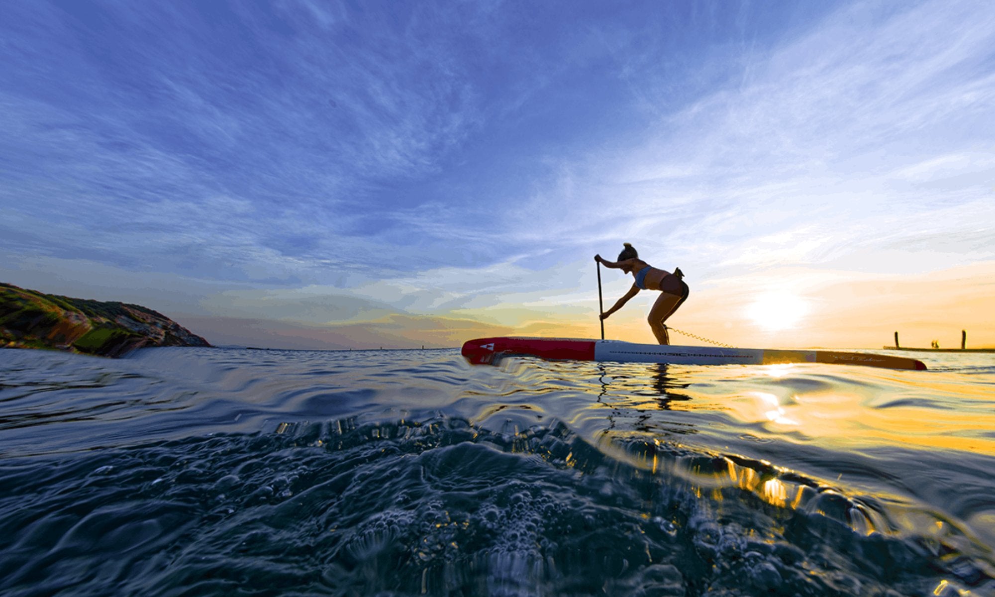 Solo paddler exploring open water on a white and red SIC Maui performance race paddleboard.