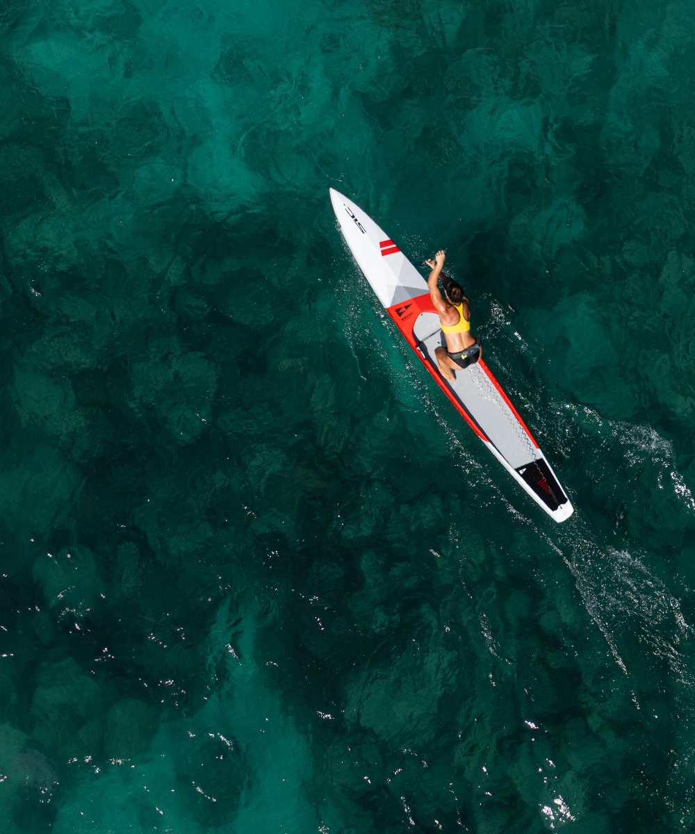Person paddleboarding on clear blue water from an aerial perspective with his RST SUP by SICMAUI