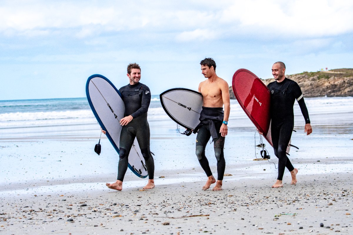 Three surfers with rigid composite surfboards of the brand SIC MAUI Surfboards