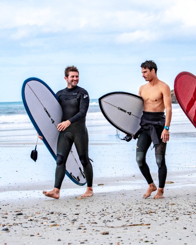 Three surfers with rigid composite surfboards of the brand SIC MAUI Surfboards